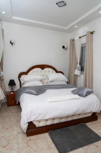 a bedroom with a large bed with white sheets and pillows at Martha House New BELL Douala in Douala