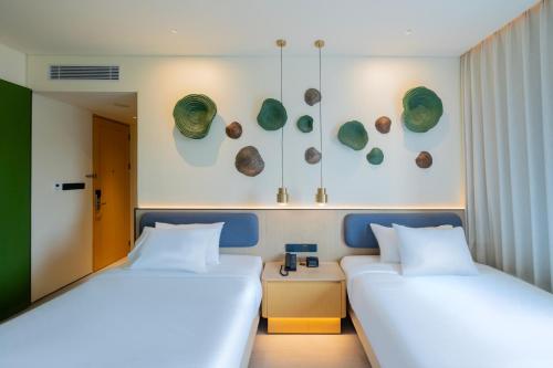 a room with two beds and a mirror at TMG Hotel Tebet, Marclan Collection in Jakarta