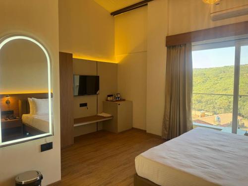 a hotel room with a bed and a large window at Regenta Z Mahabaleshwar in Mahabaleshwar