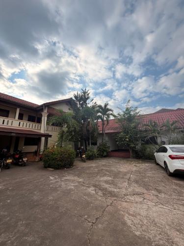 un'auto bianca parcheggiata davanti a un edificio di Singxay guesthouse ເຮືອນພັກສິງໄຊ 