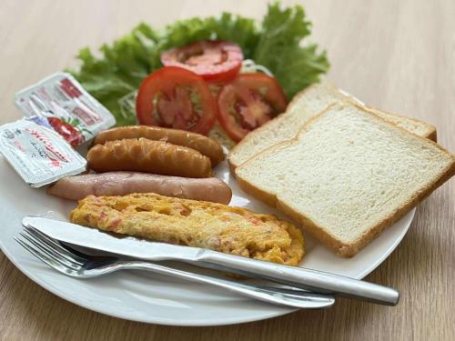 a plate of food with sausage bread tomatoes and toast at Lanta Nesta Resort in Ko Lanta Yai