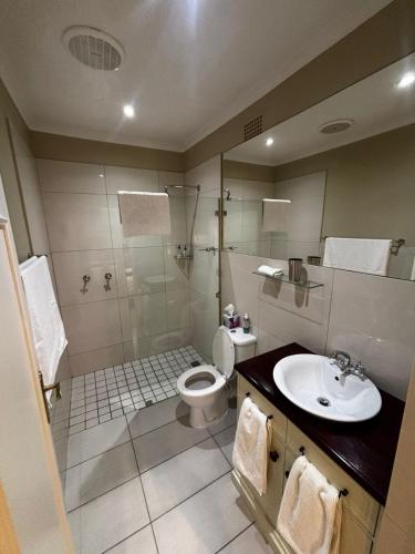 a bathroom with a toilet and a shower and a sink at Tranquil Tokai in Tokai