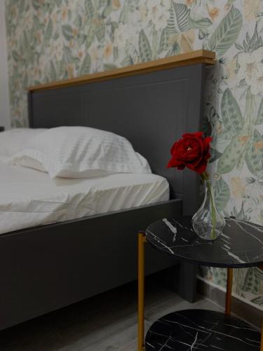 克拉约瓦Petra's的一间卧室配有一张床,一个花瓶上放着玫瑰花