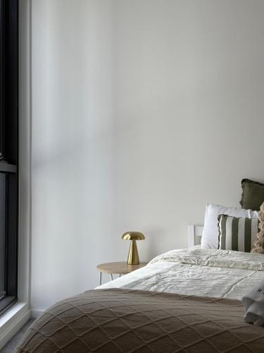 Waterfront High Rise 5 Beds 2 Car Parks في سيدني: غرفة نوم بيضاء مع سرير وطاولة