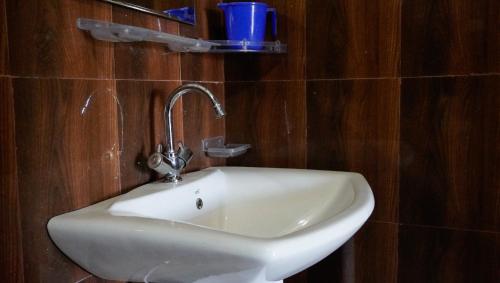 a white sink in a bathroom with wooden walls at Summer Guest House in Chauntrā