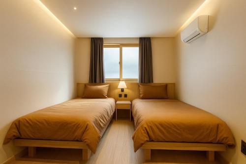two beds in a small room with a window at Well Plus Guest House in Seoul