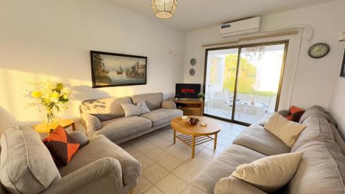 a living room with couches and a table at Sundy Beach Seaview 2BDR Larnaka Dhekelia in Larnaca