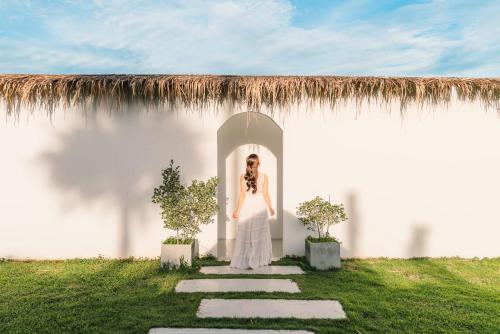 Eine Frau in einem weißen Kleid steht in einer Tür in der Unterkunft Arroon Chiang Rai, Thailand in Ban San Pu Loei