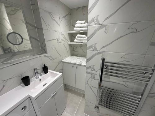 ein weißes Badezimmer mit Waschbecken und Spiegel in der Unterkunft One Bedroom Ground Floor Flat in Whitstable in Whitstable