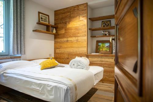 een slaapkamer met een bed en een houten wand bij L'Atelier du Temps - Maison Ida in Courmayeur