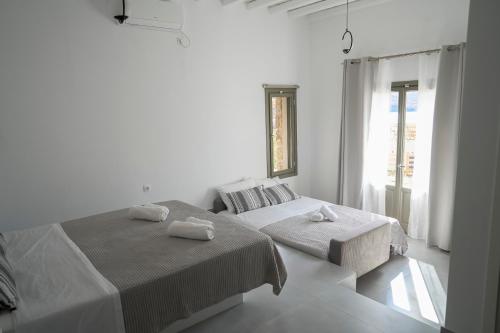 a white bedroom with two beds and a window at Remezzo in Ganema
