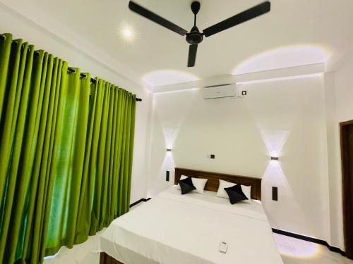 a bedroom with a bed with green curtains at THE PRASINOS villa & resort in Habaraduwa