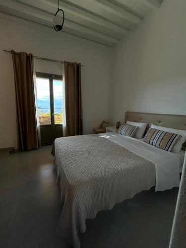 a white bedroom with a large bed and a window at Remezzo in Koutalás