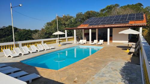 a swimming pool with chairs and a solar roof at Estância Flor do Campo in Sarapuí