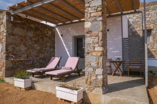 a patio with pink chairs and a stone wall at Remezzo in Koutalás