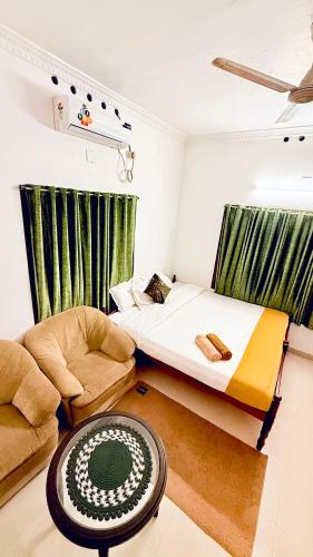 una habitación con una cama y un sofá y una mesa en Comodita Inn, en Ernakulam