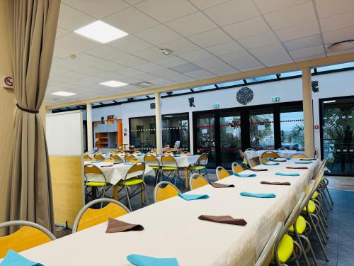 eine Reihe von Tischen und Stühlen in einer Cafeteria in der Unterkunft Hébergement Centre Missionnaire Saint Jacques in Guiclan