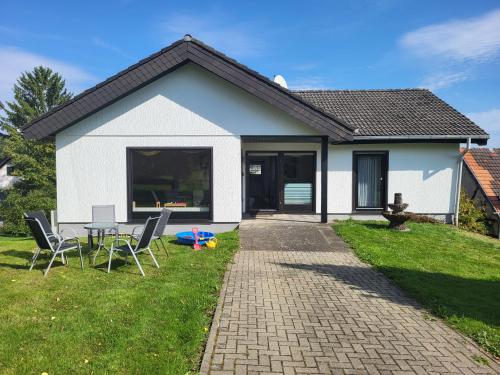 a white house with a table and chairs in the yard at Familiennest-Eifel in Blankenheim