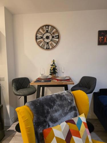 a living room with a table and a clock on the wall at Solihull 10 mins to NEC and Airport Free Parking in Solihull