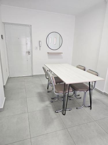 een tafel en stoelen in een witte kamer met een spiegel bij Departamento en Caseros, Prov Bs As in Caseros