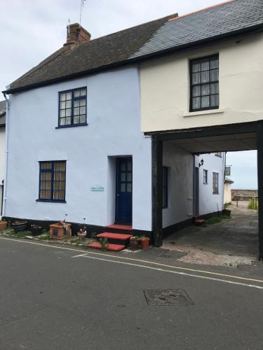 a white house with a red bench in front of it at Pier Cottage in Watchet