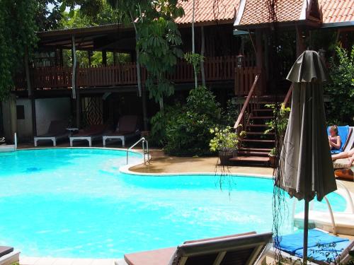 a large swimming pool with an umbrella and stairs at Harry's Bungalows in Mae Nam