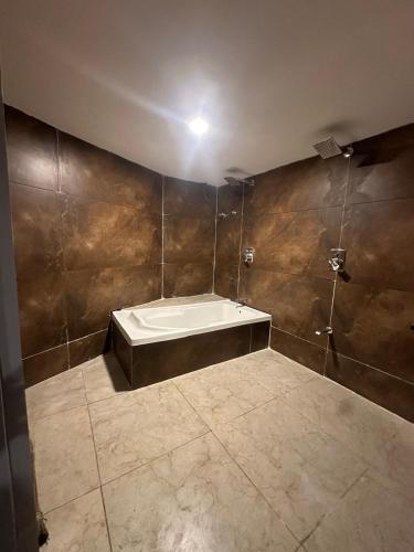 a bathroom with a tub in the corner of a room at Hotel Shyam Inn in Vadodara
