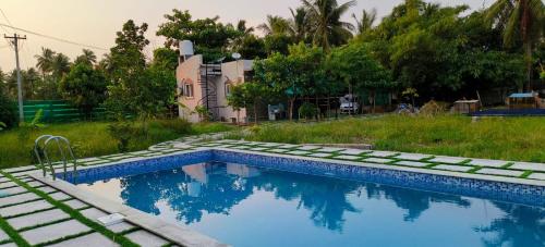 a swimming pool in the yard of a house at THE FARM CREST, ECR KADALLUR in Kūvattūr