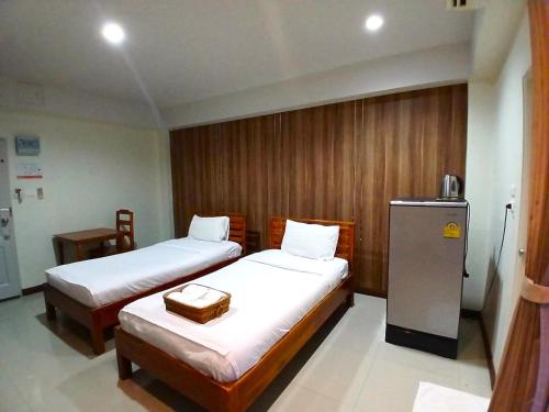 a hotel room with two beds and a refrigerator at Grand Lopburi in Lop Buri