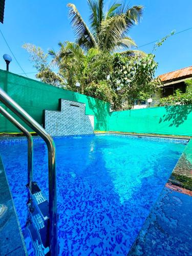 een zwembad met blauw water en een groene omheining bij yash villa in Lonavala