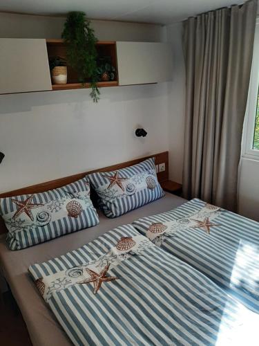 a bedroom with a bed with starfish cushions on it at Chalet Küstenzauber in Renesse