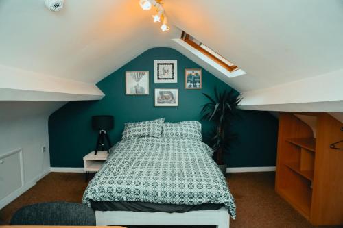 ein Schlafzimmer mit einem Bett und einer blauen Wand in der Unterkunft The Phoenix in Swansea