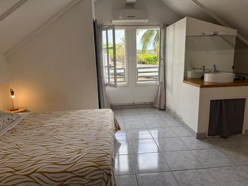 a bedroom with a bed and a kitchen with a sink at Villa Abre de l'intendance avec vue mer et piscine à Boucan Canot in Saint-Paul
