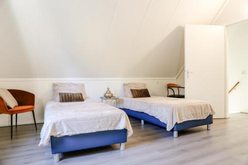 ein Schlafzimmer mit zwei Betten und einem Stuhl in der Unterkunft Comfortable family home with sauna - VP101 in Hoeven