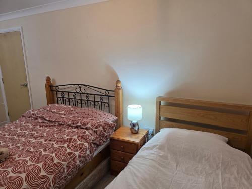 a bedroom with a bed and a lamp on a night stand at Colchester, WIFI, free parking 1 in Hythe