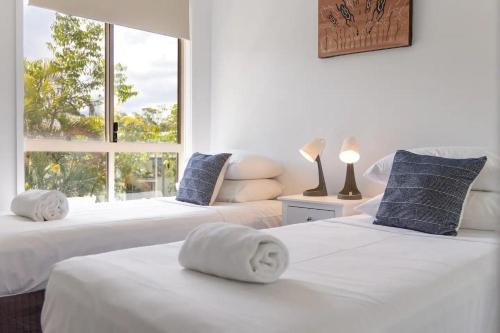 two beds with towels on them in a room with a window at Byron Lakeside Holiday Apartments in Byron Bay