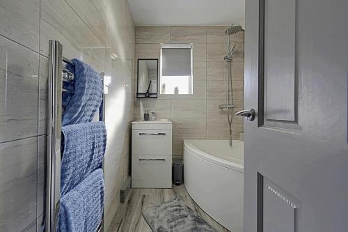 a bathroom with a tub and a toilet and a sink at Comfortable 3-Bed Home - Driveway Parking in Long Eaton