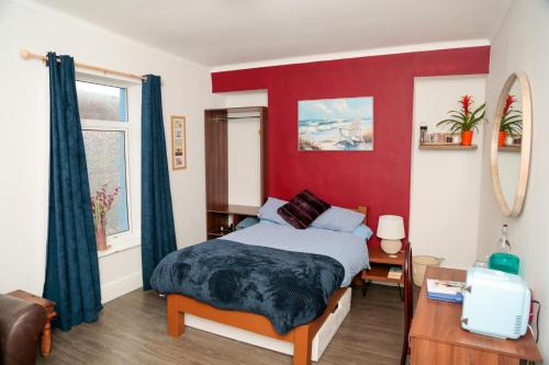a bedroom with a bed and a red wall at Amelia AirHeart in Swansea