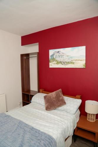 a bedroom with a bed and a red wall at Amelia AirHeart in Swansea