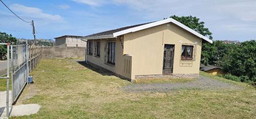 a small yellow house sitting on top of a yard at Ingeyethu Guest House in Umlazi
