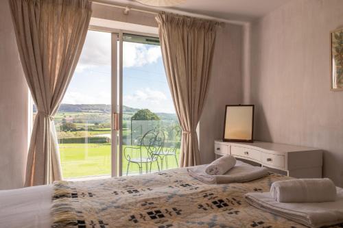 a bedroom with a bed and a large window at Greengates Nature Filled Countryside Escape 