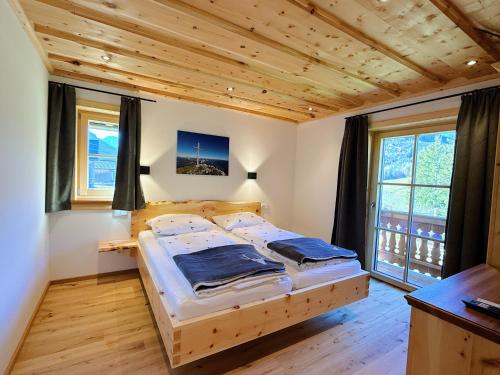 a bedroom with a wooden bed in a room with windows at Ferienhaus Bergmann in Bad Aussee