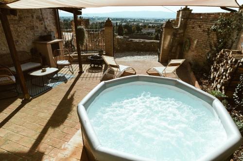 a hot tub on a patio with chairs and an umbrella at Casa di Lucy Spello - Cave Wellness & Panoramic View in Spello