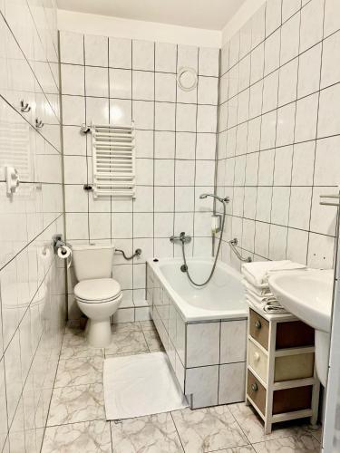 a white bathroom with a toilet and a sink at Hotel Dana in Bytów