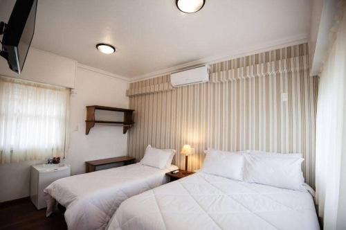 a hotel room with two beds and a window at Recanto da Ladeira in Gramado