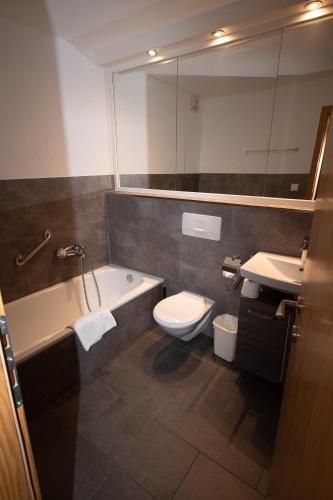a bathroom with a tub and a toilet and a sink at Chalet Gondelblick in Zell am See