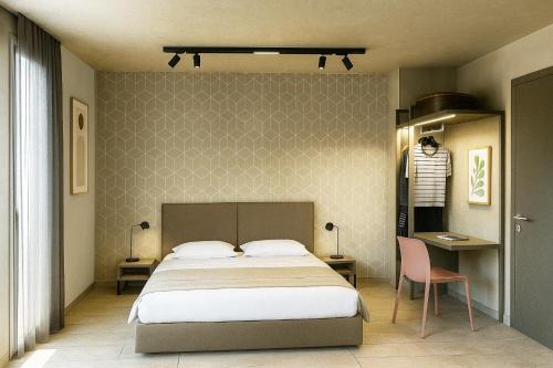 Un dormitorio con una cama, una mesa y una silla. en Hotel Costa Azzurra, en Grado