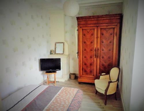 ein Schlafzimmer mit einem Bett, einem Fernseher und einem Stuhl in der Unterkunft La Roseliére in Bazenville