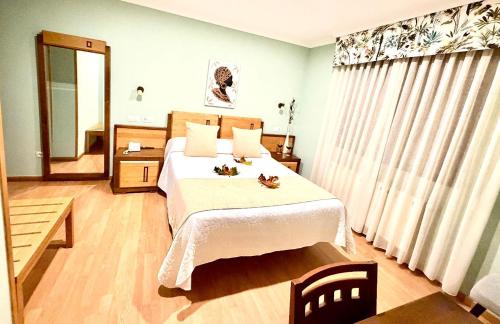 ein Schlafzimmer mit einem großen Bett mit weißer Bettwäsche und einem Spiegel in der Unterkunft Hotel Spa Galatea in Burela