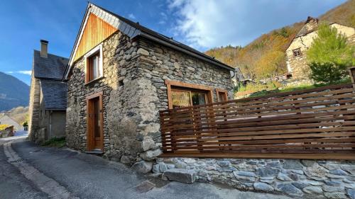 un bâtiment en pierre avec une clôture en bois dans une rue dans l'établissement Grange Aguila - Chalet au pied des pistes, à Vignec